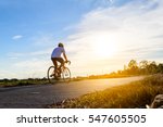 A man ride on bike on the road. Sport and active life concept sunset time. A man riding on  bicycle in a park. Blue sky with orange sun beam over the body of cyclist.
