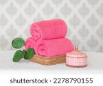 Pink terry towels rolled in a wicker basket with fragrant candles. spa set