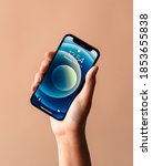Small photo of Los Angeles, California / USA - November 11, 2020: Female hand holding new black Apple iPhone mini against a colored background with screen on and clock displayed