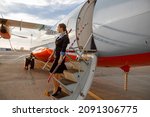 Woman flight attendant standing on airplane stairs at airport