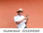 Small photo of young african female blogger holding up a mobile phone smiling posing whilst taking a camera selfie