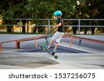 Small photo of A boy on a scooter and in protective helmet do incredible stunts in skate park. Extreme jump. The concept of a healthy lifestyle and sports leisure