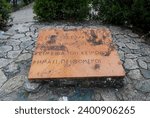 Small photo of Thermopylae, Greece - September 26th, 2022: Commemorative stone placed on top of burial mound of Spartans with epigram as epitaph. Selected focus.