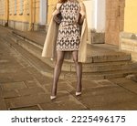 a girl with long red hair, in a short skirt, fishnet tights, shoes, walks around the city, during the day. Street fashion, style, high heel, autumn
