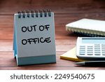 Out of office text on calendar desk with notebook, calculator and pen background. Out of office concept