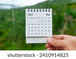Hand holding May 2024 white calendar with nature background. Holiday and calendar concept.