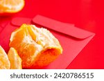 Small photo of Peal Mandarin oranges on top of Chinese New Year red packet. Chinese New Year celebration concept.