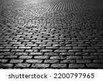 Old cobblestones on Market place “Grote Markt“ in Antwerp Belgium. Shiny historic basalt ashlars and blocks reflecting sunshine. Pavement background, black and white greyscale with high contrast.