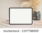 Tablet empty white screen with pencil mock-up. Cotton flower and dry leaves on beige background mockup for design