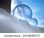 Small photo of Dubuque, Iowa, January 19, 2024 – close-up photo of beautiful bubbles sitting on a snow bank, freezing in frigid temperatures under cloudy blue sky.