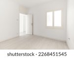 Small photo of View of an empty white bright room with window without furniture after painting and renovation with wooden floor and baseboards. Concept of beautiful laconic interior for various inspiring ideas