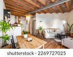Compact but smartly divided studio with rustic style living and kitchen areas with wood beamed ceiling and comfortable furniture in beige tones. Concept of laconic interior design