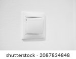Small photo of Standart rocker switch for exhaust fan or lighting applications. White common toggle switch in home. Inexpensive plastic push button switch against white wall. Cheap simple single-pole light switch
