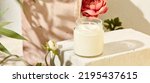 Small photo of Composition with aromatic candle in jar on concrete podium. Mockup soy wax candle in natural style with flower. Scented handmade candle with wick. Handmade spa product from soy wax in glass