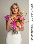 Small photo of Vertical calm, elegant, beauteous blond female bride in white dress with bouquet of colorful flowers in studio. Greetings and festive event. Wedding, engagement and just married. Copy space, mockup