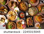 Small photo of Abundance snack and fast food on wooden table in restaurant. Tomato soup, sauce, hamburger, french fries with chicken meat, pasta with shrimps, sea food, pizza sandwich and alcohol drinks. Full frame
