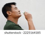 Small photo of Asian man uses inhaler to smell for relieve dizzy and faint symptoms. Concept , health problem, sickness and remedy. Increases freshness, reduces dizziness and stuffy nose. self take care.