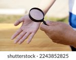 Small photo of Closeup hand holds magnifying glass to inspect palm lines. Concept : palmistry, astrology. Foretelling, mystery, magic, fortune, fate. Prediction for future life , events. Palmist predicting.