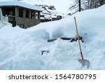 After huge snowfall in January 2018, Valtournenche, Cervinia, Italy. A car under a snowdrift and a shovel in the foreground