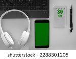 Small photo of calendar date on a light background of a desktop and a phone with a green screen. June 30 is the thirtieth day of the month.