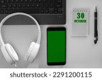 Small photo of calendar date on a light background of a desktop and a phone with a green screen. October 30 is the thirtieth day of the month.