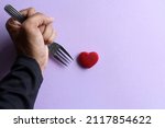 Small photo of Betrayal, disloyalty and backstabbing concept. Hand stab red heart using fork.