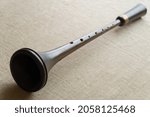 Small photo of Shawm (schalmei, schalmeien) , a brown medieval wooden folk wind musical instrument with a metal decor, lies on a gray canvas