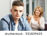 Small photo of Bored Teenage Boy Being Told Off By Mother
