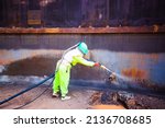 Small photo of sandblasting process Sandblasting industrial workers prepare to clean steel surfaces of oil drums before painting in the factory.