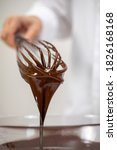 Small photo of Closeup pouring tasty dark melted couverture chocolate on whisk isolated on white background. Chocolatier making premium hand-crafted chocolate. Candy making, pastry bakery production, dessert concept