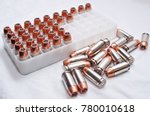 A plastic shell container holding .40 caliber hollow point bullets with a portion of them laying next to it, shot on a white background