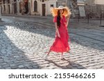 Summer clothes: straw hat, sunglasses, red polka-dot dress and white sneakers. Stylish girl walk on old city streets
