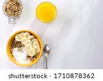 Healthy breakfast of muesli with banana and yogurt, orange juice on a white wooden background