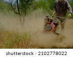 Small photo of Man working in the garden with garden tiller. tractor cultivating and loosens soil field