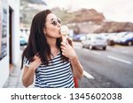 Pretty brunette girl eating ice cream and walking outdoor on the street