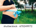 Small photo of Closeup photo of pregnant woman outdoor with present riband on abdomen