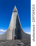 Small photo of Reykjavik, Iceland, 14.05.22. Hallgrimskirkja modernist church resembling basalt columns in Reykjavik, Iceland, modern belfry and wings against clear blue sky, symmetrical view.