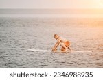 Active mature male paddler with his paddleboard and paddle on a sea at summer. Happy senior man stands with a SUP board. Stand up paddle boarding - outdor active recreation in nature.