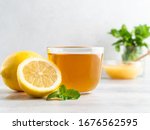 A glass cup of fresh green herbal tea with lemon, honey and green mint leaves. White background, close up view, copy space.