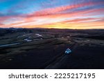 Aerial view of 4wd car parked on dirt road among moss lava field in the sunset on Icelandic highlands in summer of Iceland
