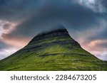 Close up of Moody Kirkjufell mountain peak with cap cloud covered in the sunset on summer at Iceland