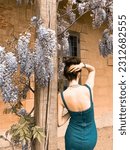 Small photo of a woman in denim dress from behind by blooming flowers near little Marie Antoinette's house