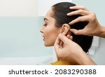 Small photo of Installation hearing aid on woman's ear at hearing clinic, close-up, side view. Deafness treatment, hearing solutions
