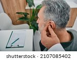 Small photo of Audiologist fits a hearing aid on deafness mature man ear while visit a hearing clinic. Hearing solutions for older