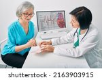 Small photo of Doctor cardiologist analyzes heart electrocardiogram results of senior female while consultation. Diagnosis of heart rate and heart disease of older people
