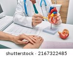 Small photo of Cardiology consultation, treatment of heart disease. Doctor cardiologist while consultation showing anatomical model of human heart