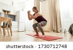 Small photo of Full length shot of young curvy woman in sportswear exercising using resistance band at home. Determination, will power, sport concept. Horizontal shot