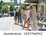 Full length shot of people wearing masks waiting, standing in line, keeping social distance at bus stop. Coronavirus, pandemic concept. Selective focus on guy in the queue. Horizontal shot