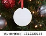 Blank Round Christmas Ornament hanging from a lit up Christmas tree surrounded by ornaments. 