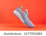 Small photo of Stability and cushion running shoes. New unbranded running sneaker or trainer on orange background. Men's sport footwear. Pair of sport shoes.